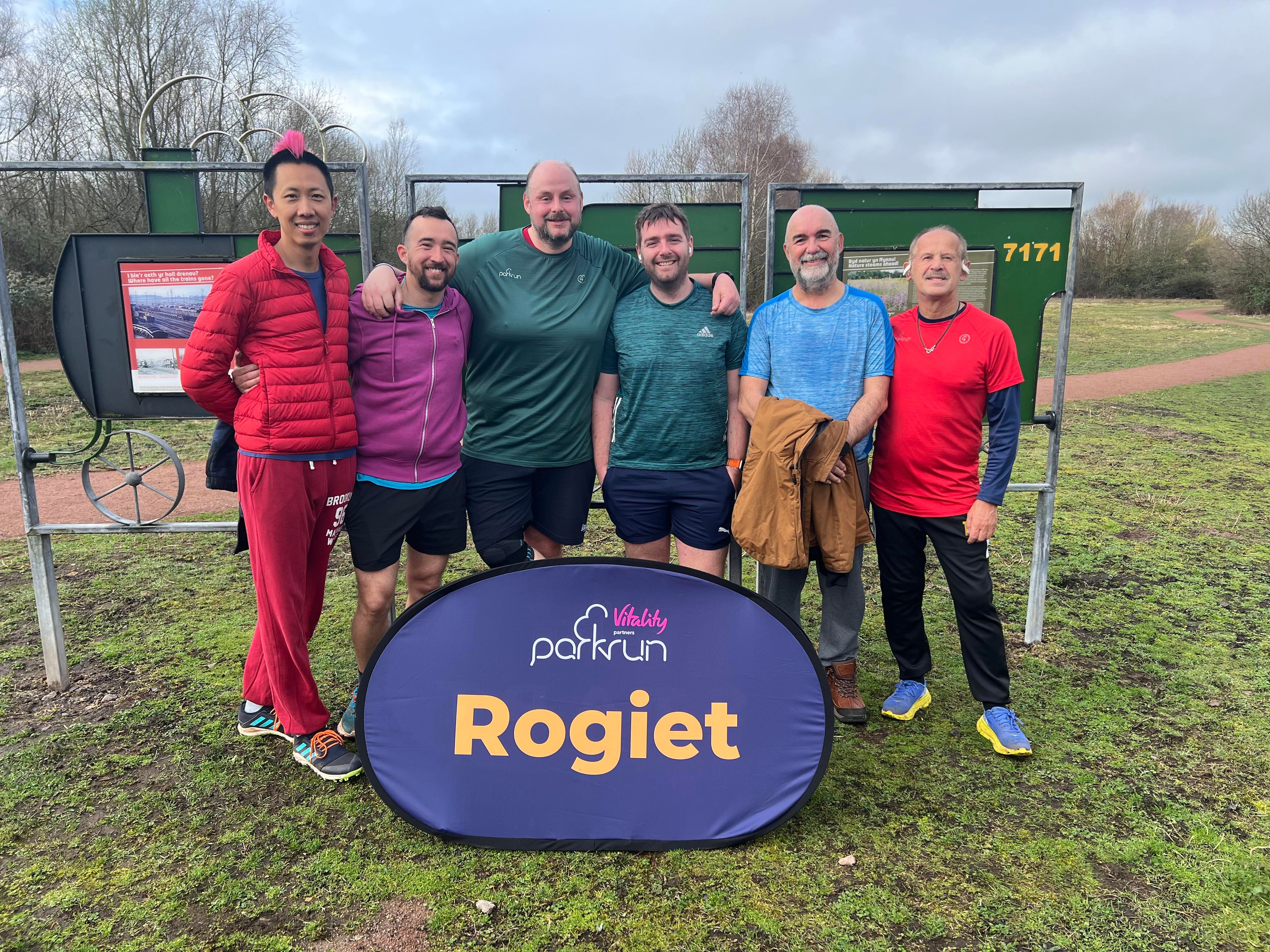 Vince and friends stood behind parkrun sign and smiling at camera